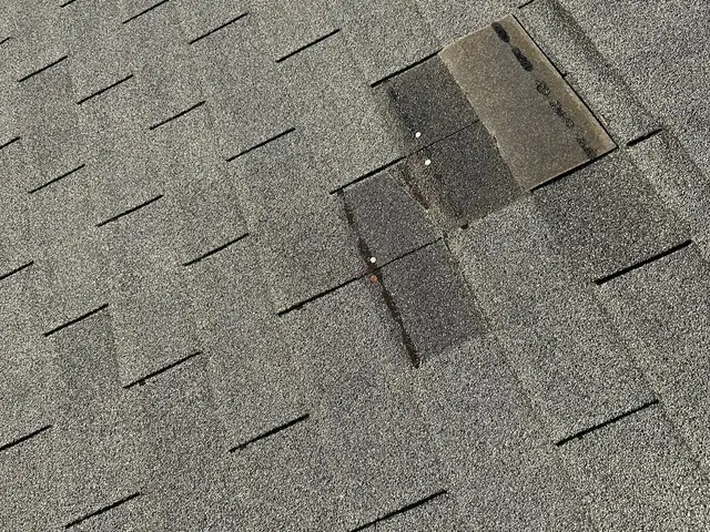 Shingle patch repair on a gray asphalt roof by Lopez Brothers Roofing